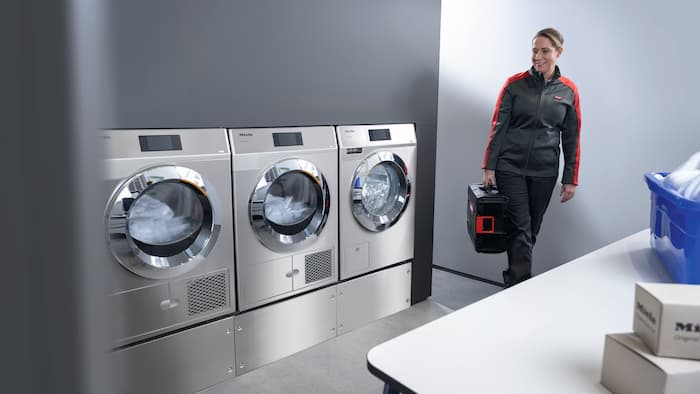 Miele service technician approaching washing machines with a toolbox
